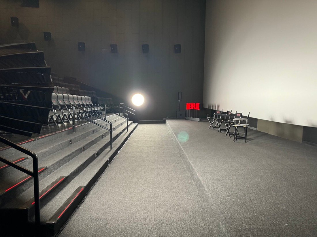 Interior bioskop dengan lightbox Netflix menyala dan kursi sutradara berlogo